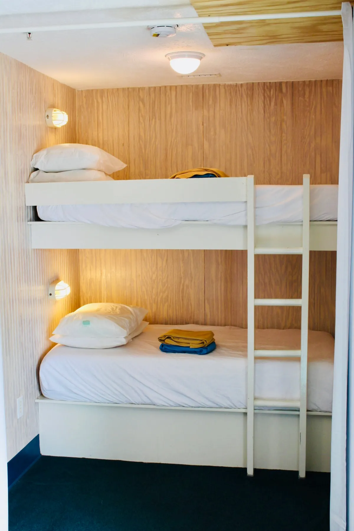 An inviting scene with bunk beds, neatly arranged pillows, and folded blankets. The playful arrangement suggests a practical yet comfortable space where travelers can relax in between beach outings or prepare for a day of fun.